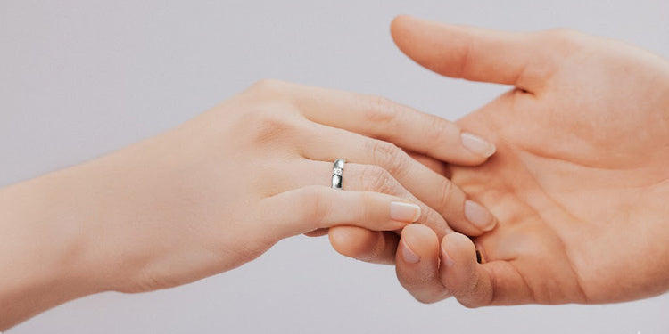 Paar hält Hände - Weißgoldener Ring mit Diamant am Finger 