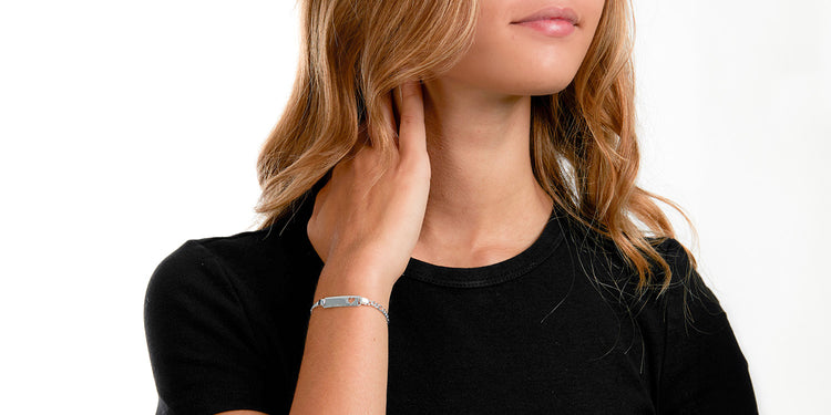 Frau in schwarzem Top trägt silbernes Gravur-Armband mit rechteckigen Gliedern am Handgelenk